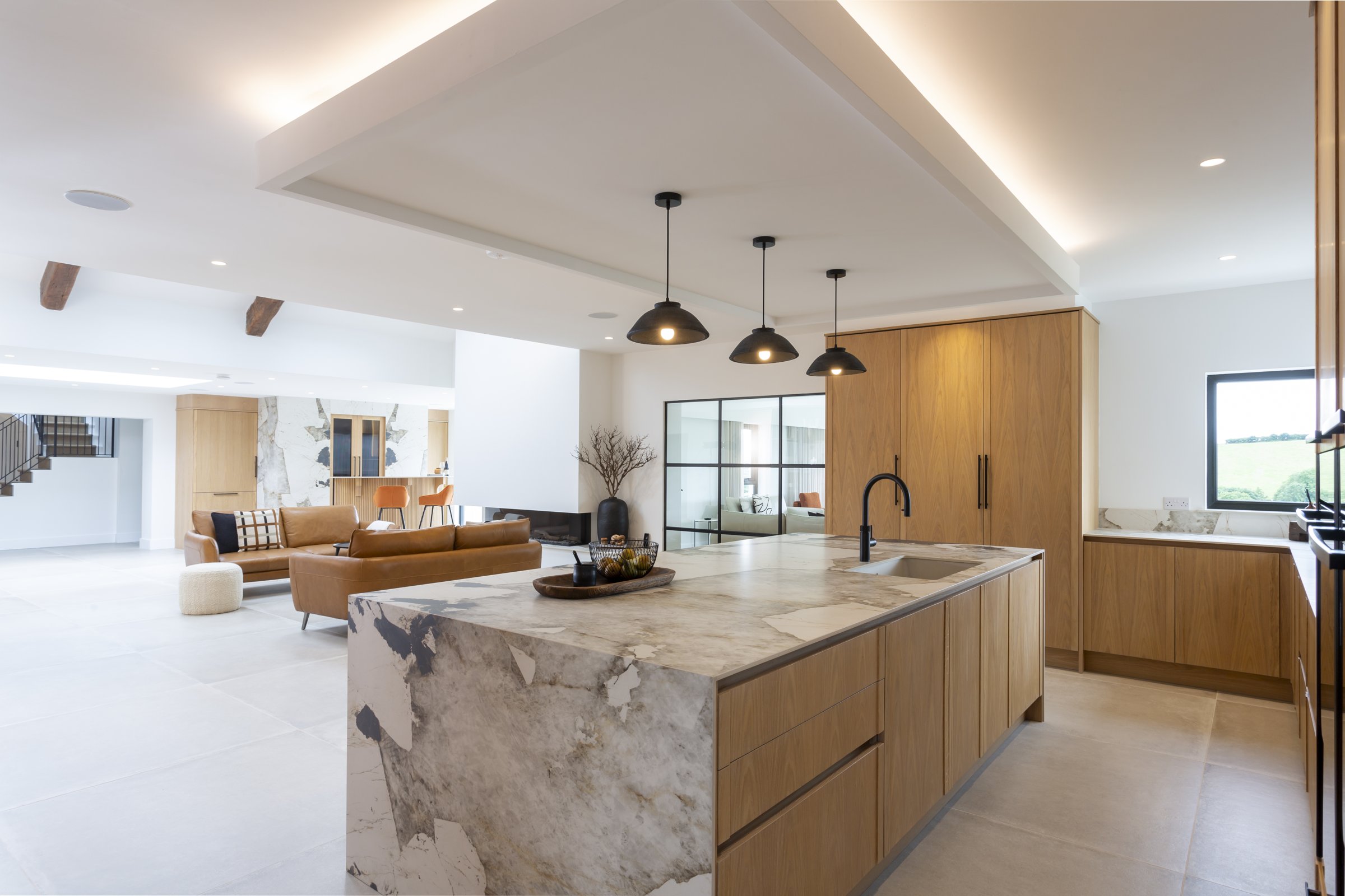 Ligna oak kitchen with a veined stone island, black tap and open-plan dining area