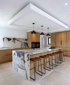 Wide view of the Ligna kitchen island, oak cabinetry and black pendant lights