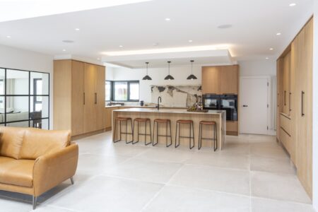 Open-plan Ligna kitchen with oak cabinets, stone island and adjoining living area