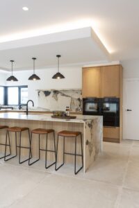 Ligna island seating with oak cabinetry and integrated ovens behind