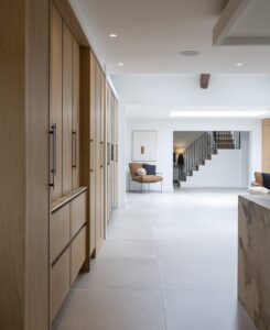 Detail of Ligna oak cabinet doors with long dark handles beside the hallway