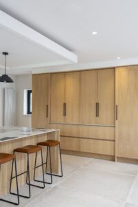 Ligna oak storage cabinets with closed pocket doors beside the island