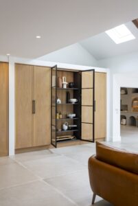 Ligna oak cabinetry and black-framed glazed display cabinet beside the living area