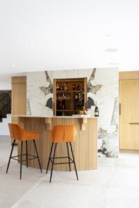 Ligna home bar with illuminated oak shelving and two orange stools