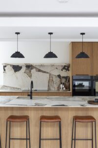 Ligna kitchen island seating with stone splashback and integrated ovens behind