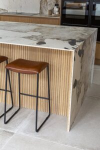 Detail of fluted oak on the Ligna island beneath the stone worktop and leather stool